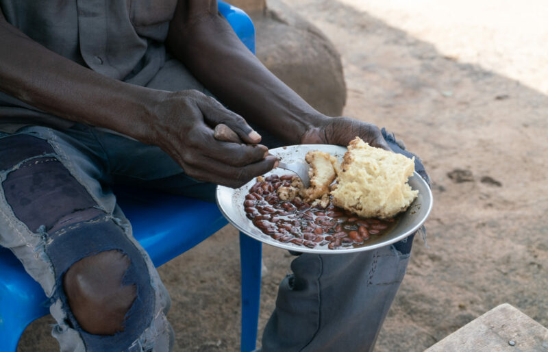 Hands holding a bowl of beans and maize porridge