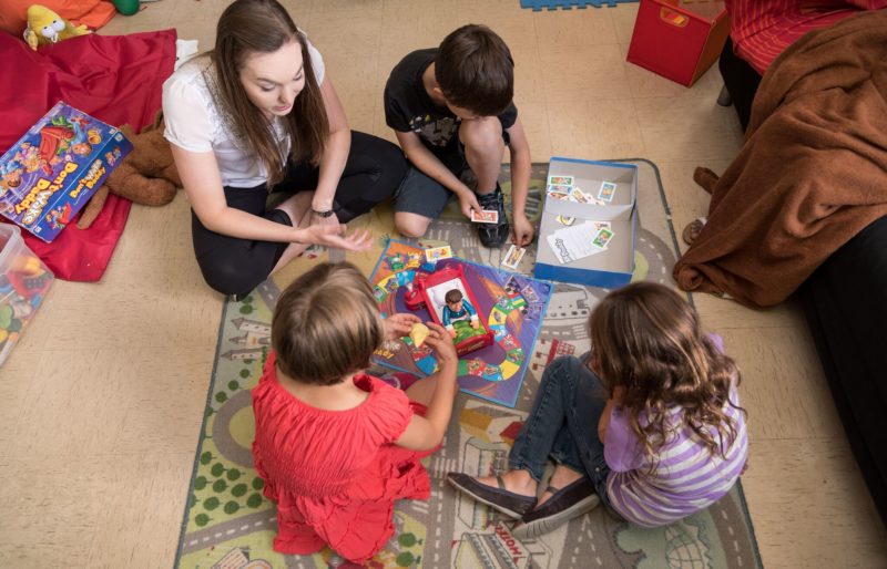 Autism instructor and three children playing boardgame on the floor