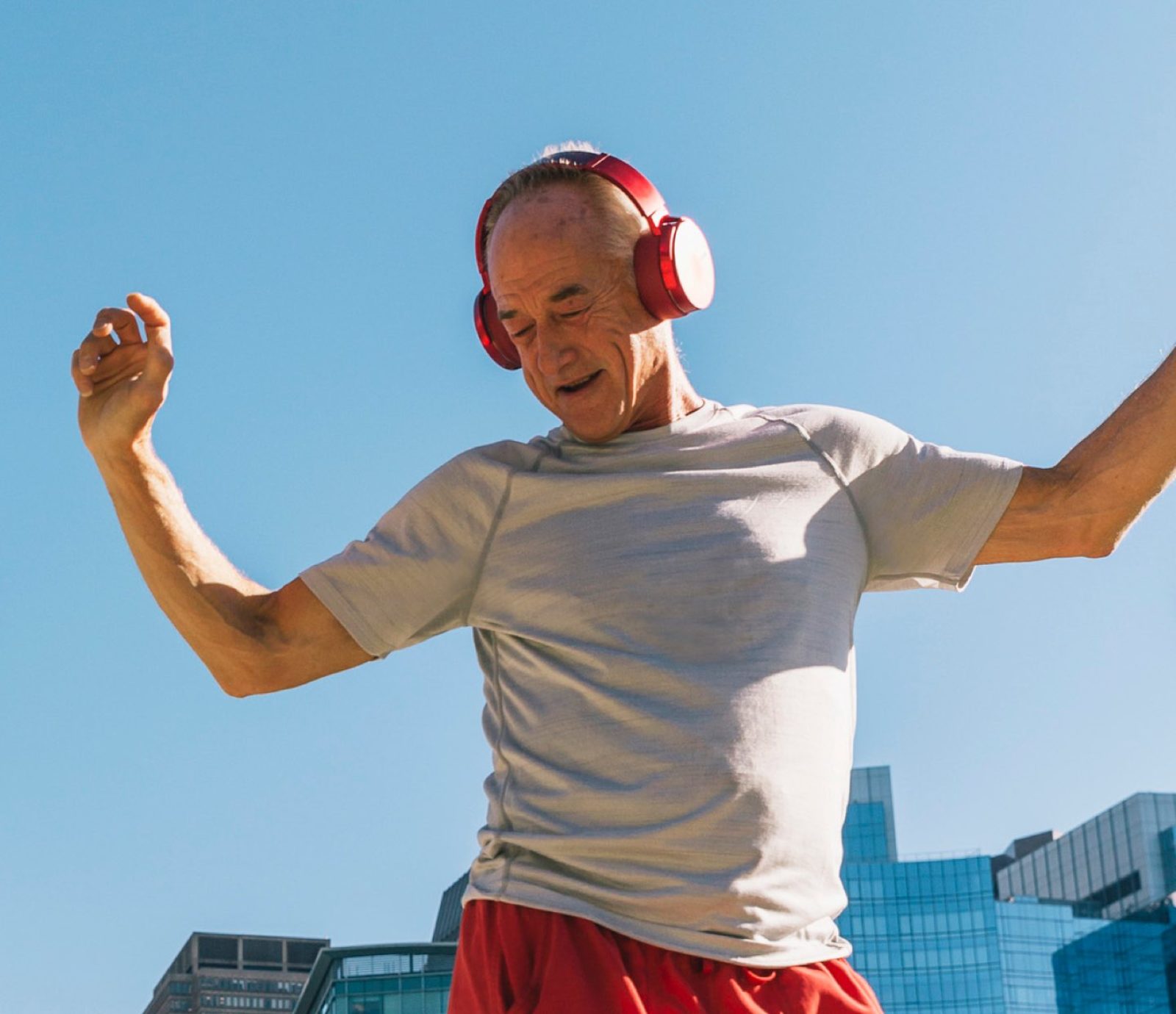 Older man jumping against a blue sky