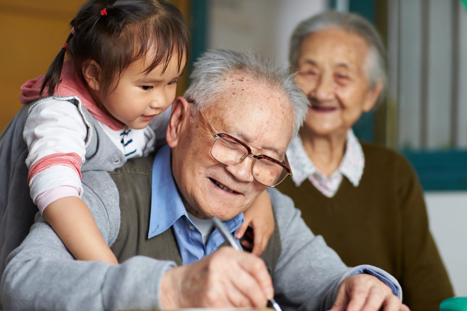 Young girl and great grandfather writing together