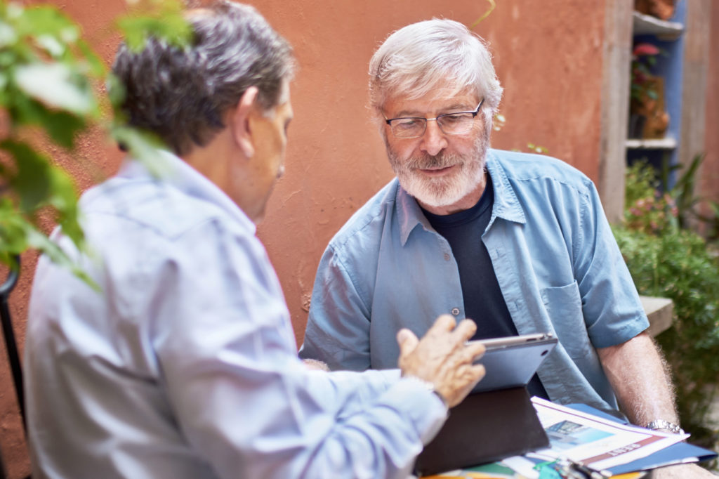 Two men discussing a plan on a tablet computer outdoors