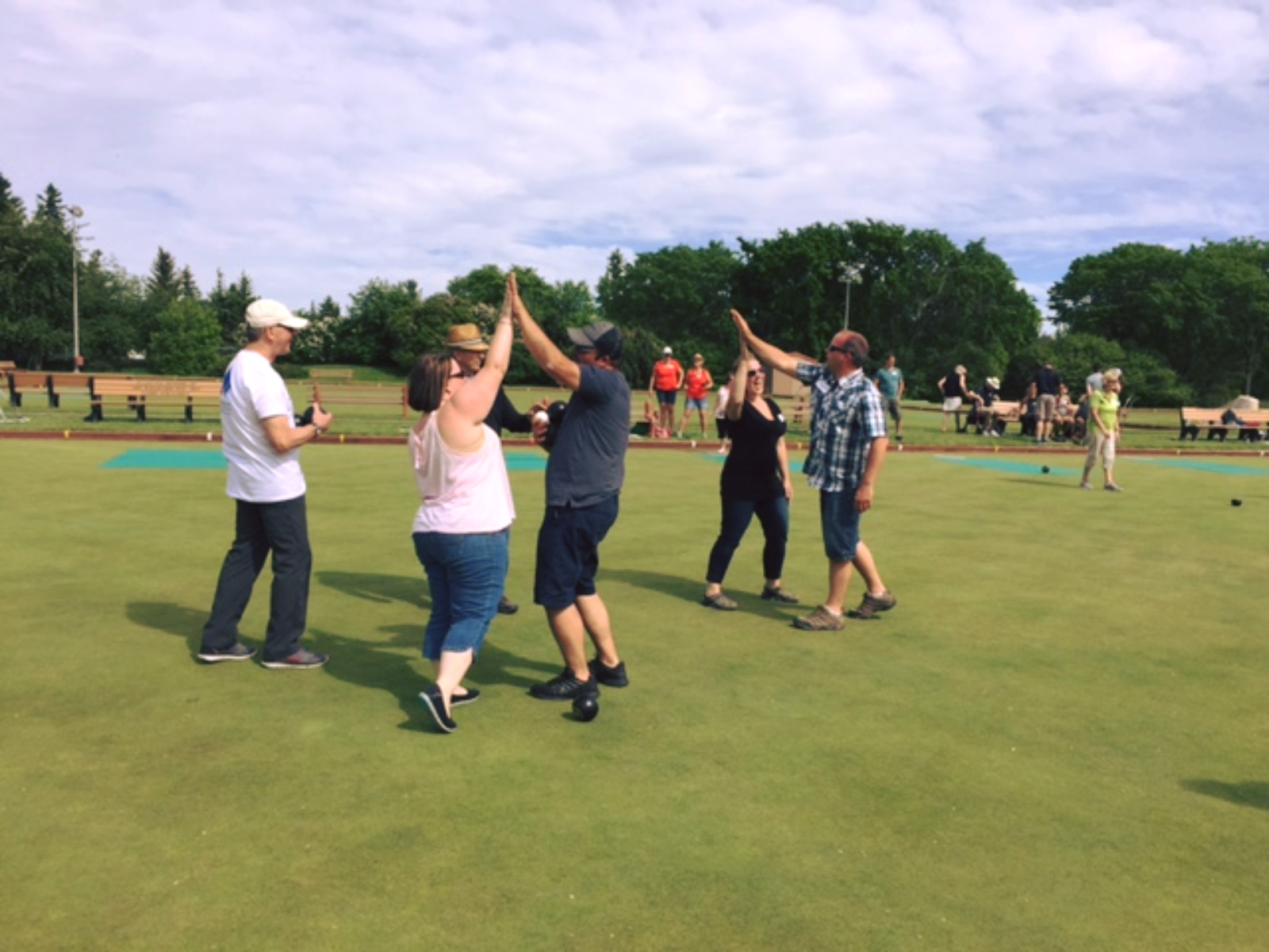 Lawn bowlers high-fiving on a green