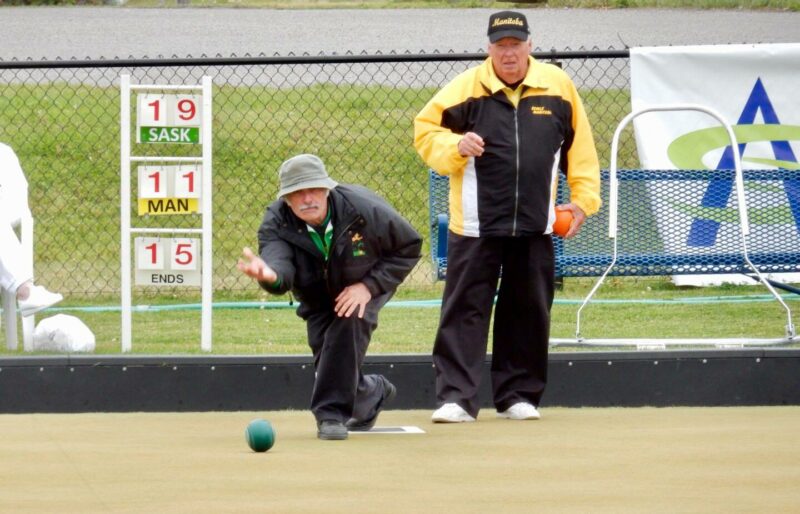 A senior male delivering a lawn bowl