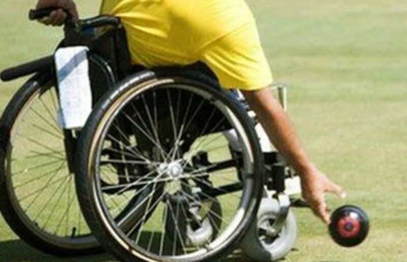 Person in a wheelchair rolling a lawn bowl
