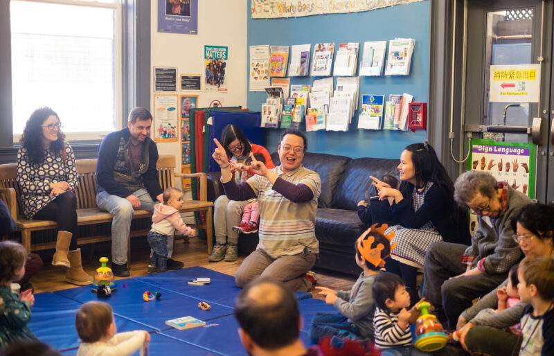 Person in the center of the room surrounded by children.