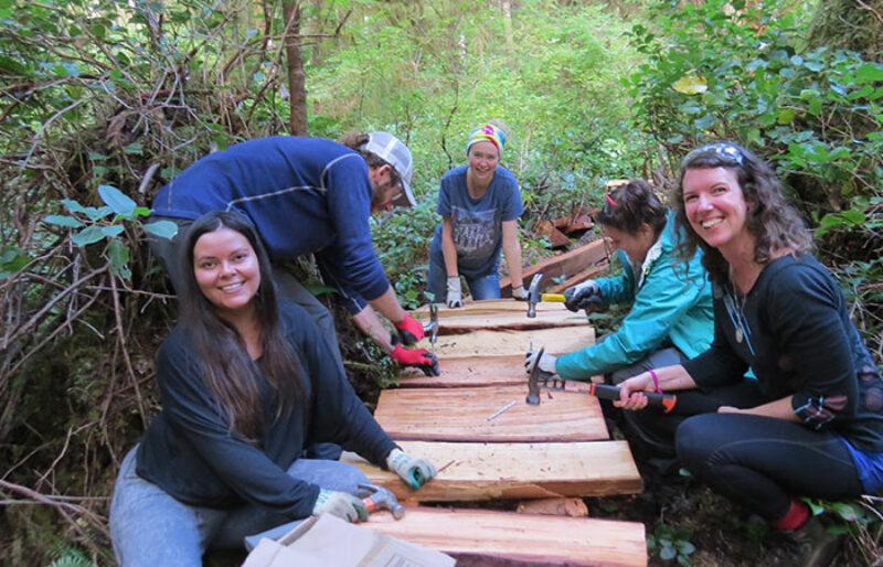 A few volunteers pose while nailing cedar planks into the boardwalk.