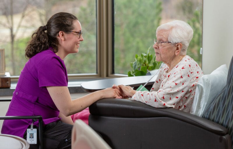 A care provider holds a patient's hands.