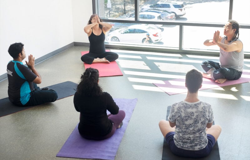 People sitting on yoga mats in a room.