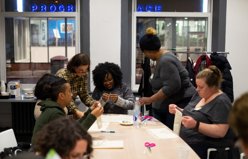 People sitting at a table with sewing projects.