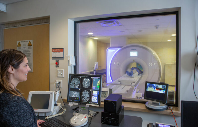 a doctor looks through the window at a patient getting a ct scan