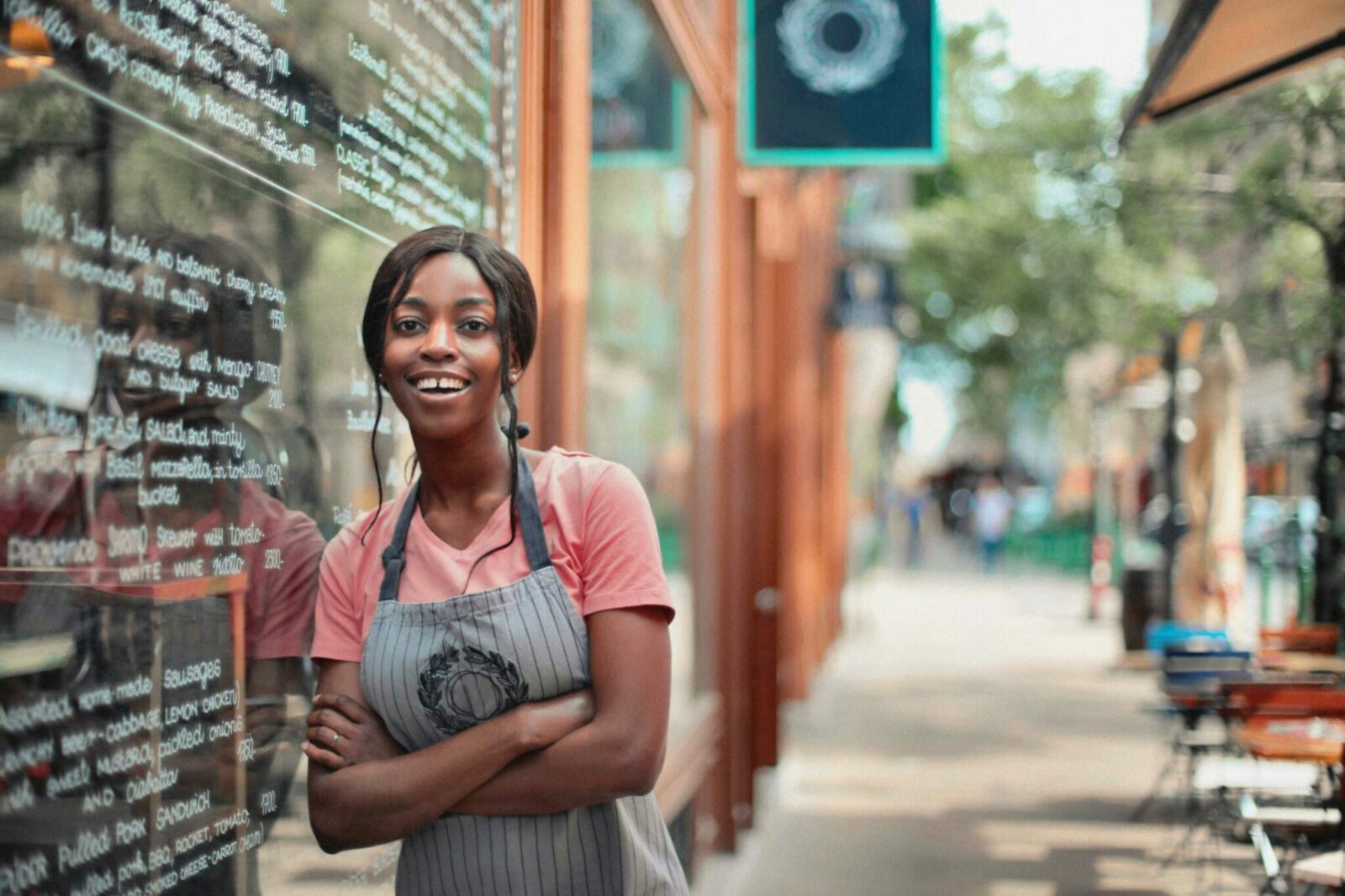 Woman in apron leaning against her shop window