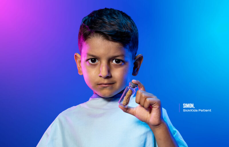 Simon, a SickKids patient with an allergy, is shown holding a glass vial with a peanut.