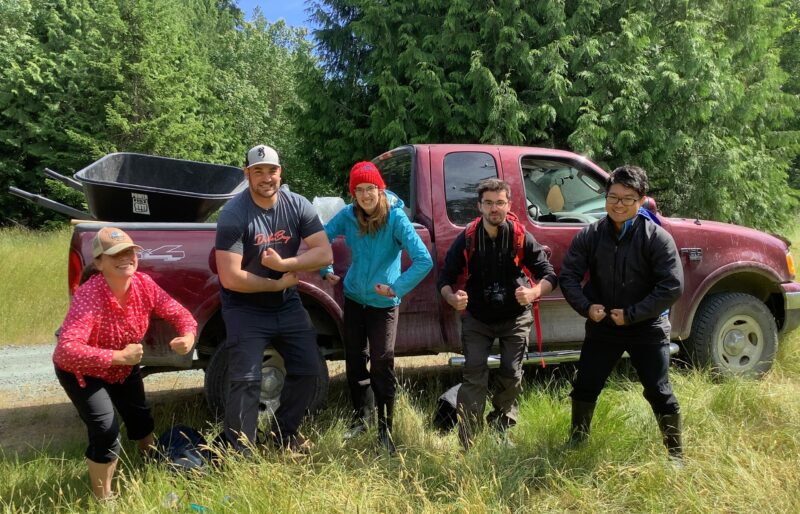 5 young people grinning, by a truck