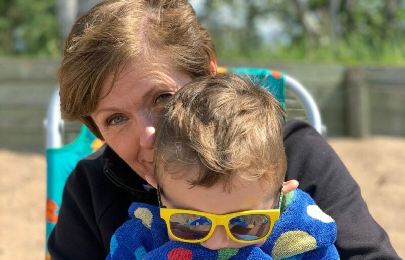 A grandma and grandson enjoy a snuggle on the beach at Waskesiu Lake