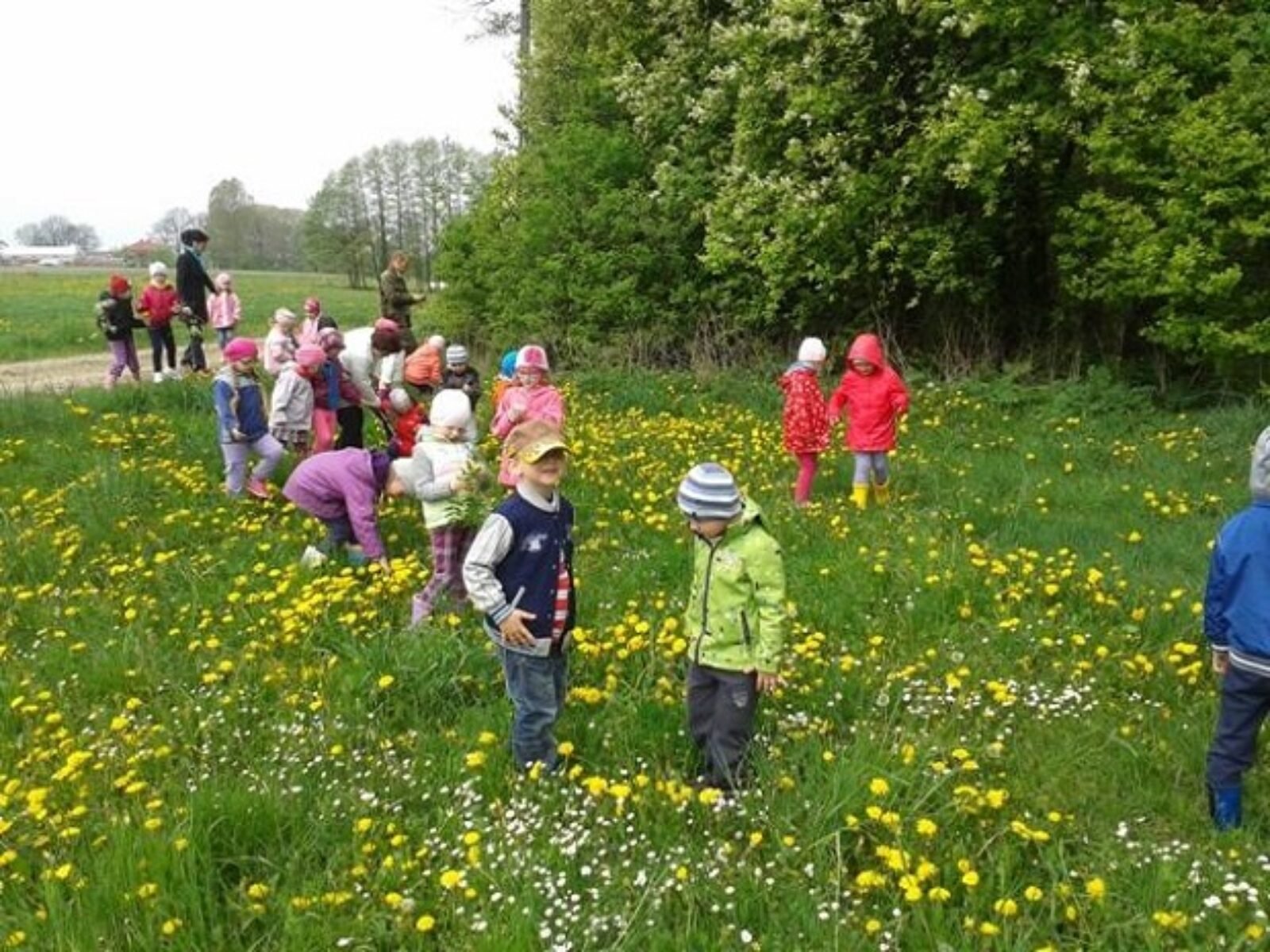 Primary grade students in spring coats walking through a field.