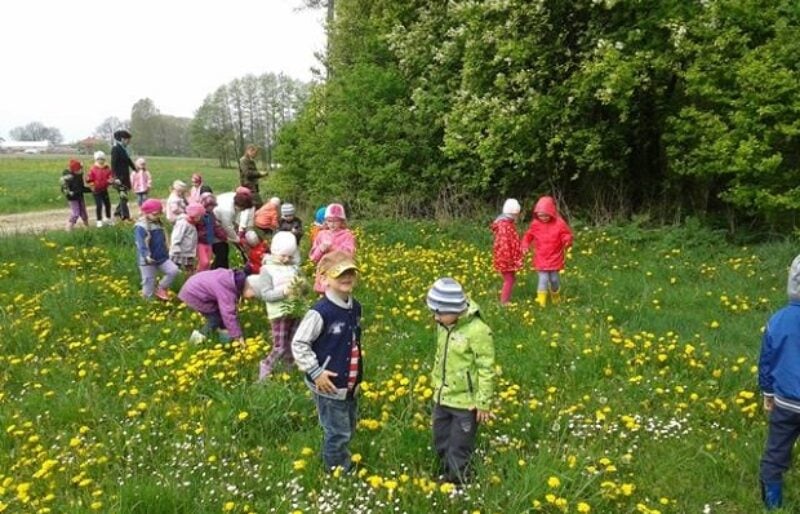 Primary grade students in spring coats walking through a field.