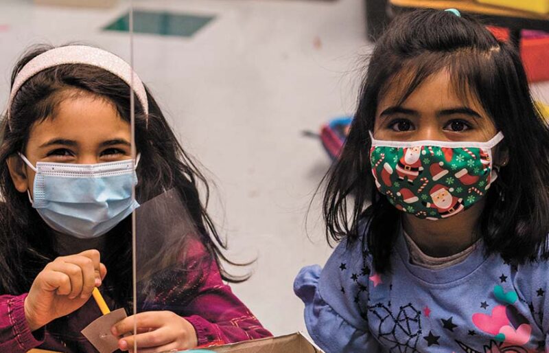 Two girls in masks, playing and smiling together