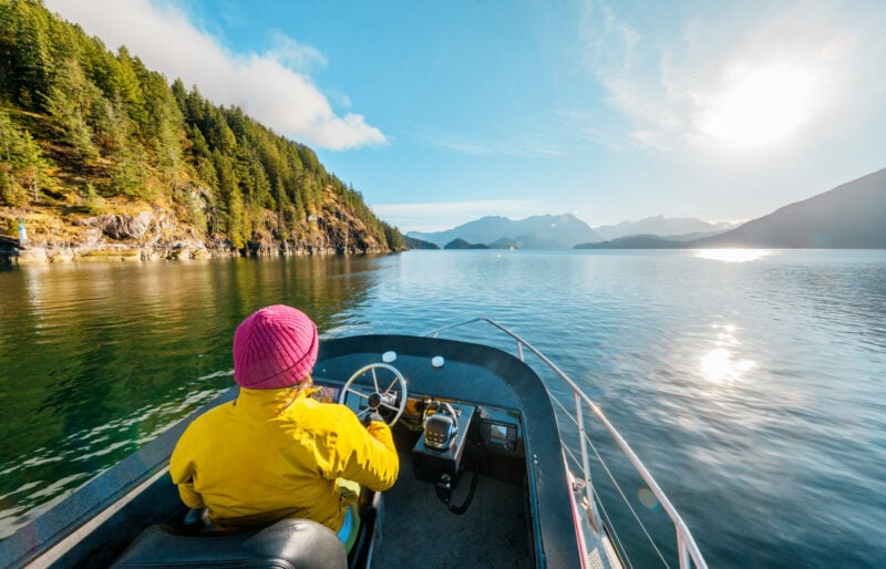 Woman Driving Motor Boat in Amazing Nature Landscape at Sunset in Coastal British Columbia Near Bute, Toba Inlet and Campbell River.