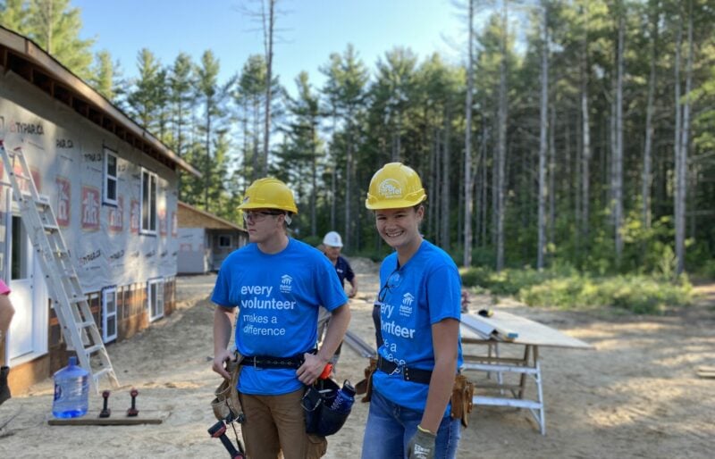 Two people wearing construction gear while helping build a house for Habitat for Humanity