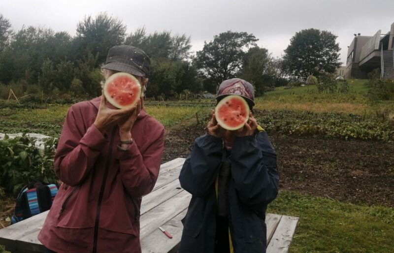 Photo of two gardeners with watermelon covering their faces