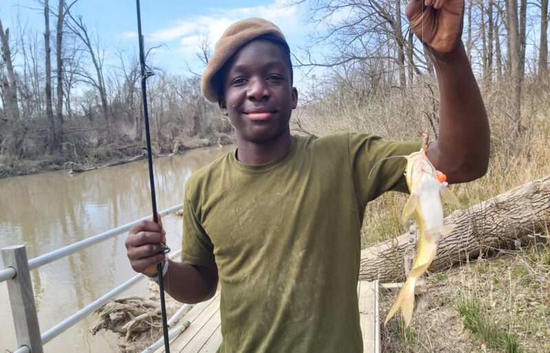 Boy holding fishing pole and a fish.