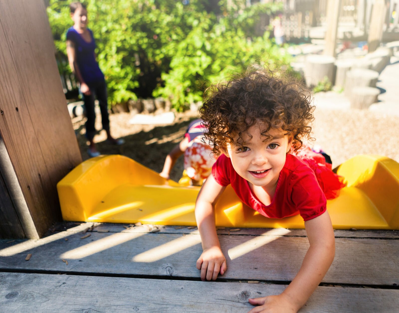 Toddler at the top of a slide smiling
