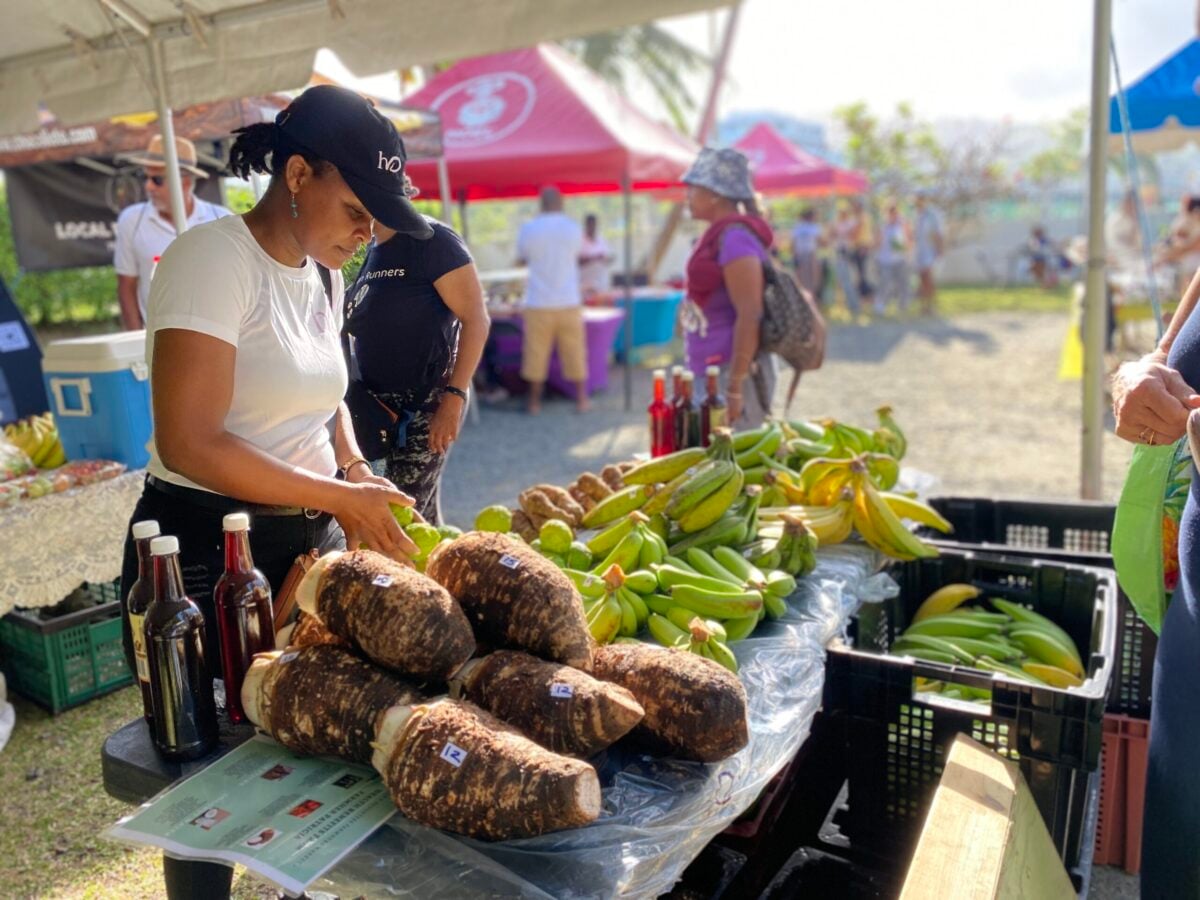 A woman is setting up a farmers market stall with bananas.
