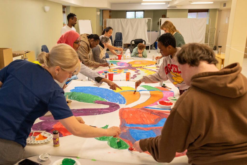 People with and without intellectual disabilities painting a mural together in an inclusive L’Arche community in Winnipeg.