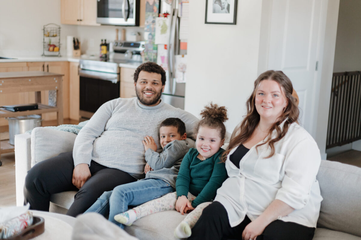 family of four sitting on their living room sofa