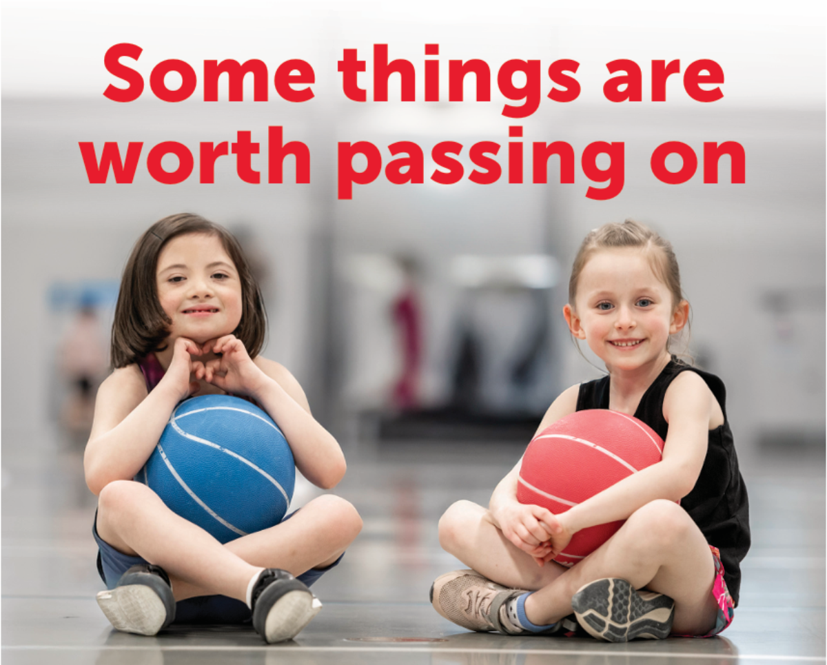 Two young girls playing basketball in a YMCA Gymnasium